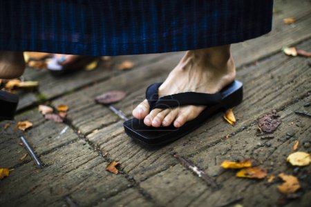 Photo for A man 's feet in black sandal on a wooden background. - Royalty Free Image