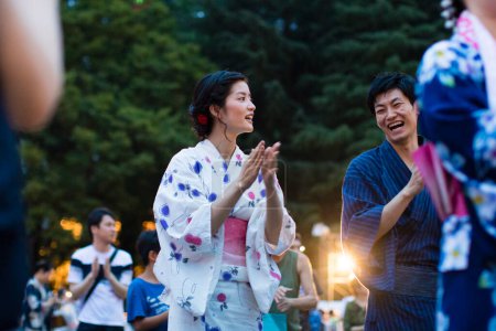 Photo for Young Japanese couple wearing traditional kimono dancing in evening park - Royalty Free Image