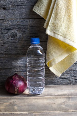Foto de Botella de agua dulce y cebolla morada sobre una mesa de madera. - Imagen libre de derechos