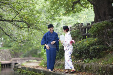 Photo for Young Japanese couple wearing traditional kimono in summer park - Royalty Free Image