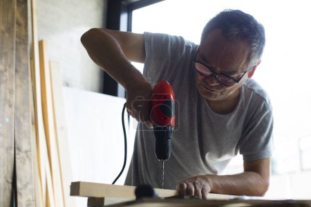 Foto de Vista de cerca del carpintero masculino que trabaja en la mesa en el taller industrial - Imagen libre de derechos