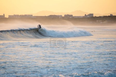Téléchargez les photos : Surfeur chevauchant une vague de mer au coucher du soleil, loisirs actifs - en image libre de droit