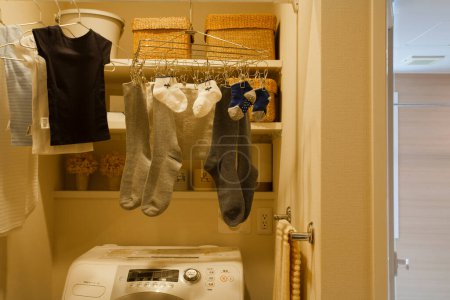 Photo for A laundry room with a washing machine and clothes hanging - Royalty Free Image