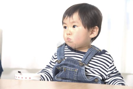 Photo for Portrait of cute little Asian boy eating at home - Royalty Free Image