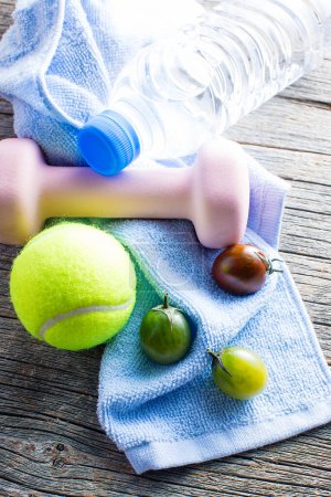Photo for Tomatoes, glass of water, towel, tennis ball and dumbbell on wooden table - Royalty Free Image