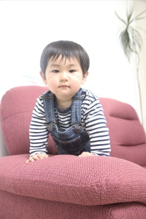 Photo for Asian little boy sitting on pink sofa - Royalty Free Image