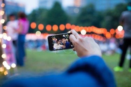Photo for Young Japanese couple wearing traditional kimono taking selfie on smartphone in park - Royalty Free Image