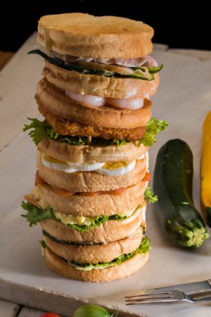 Foto de Pila de sándwiches caseros con pechuga de pollo, lechuga, queso, huevos y camarones - Imagen libre de derechos