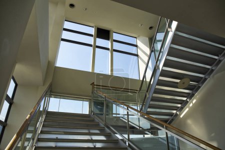 Téléchargez les photos : Escaliers dans un immeuble de bureaux moderne vide avec fenêtres et lumière du soleil - en image libre de droit