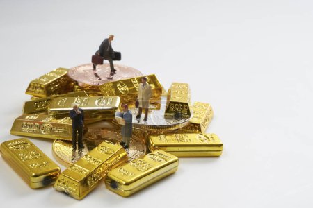 Téléchargez les photos : Figurines miniatures d'hommes d'affaires debout sur un tas de bitcoins et de lingots d'or - en image libre de droit