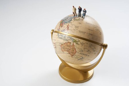 Foto de Figuras de personas en miniatura de pie en la parte superior del modelo de globo terráqueo sobre fondo blanco - Imagen libre de derechos
