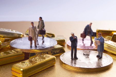 Téléchargez les photos : Figurines miniatures d'hommes d'affaires debout sur un tas de bitcoins et de lingots d'or - en image libre de droit