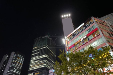 Téléchargez les photos : Rue éclairée avec bâtiment de centre commercial à Tokyo la nuit, Japon - en image libre de droit