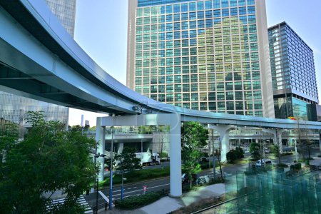 Photo for Pedi Shiodome shopping complex at the background of New Transit Yurikamome elevated railway line at Shiodome area of Minato. Tokyo. Japan - Royalty Free Image