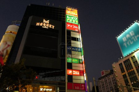 Téléchargez les photos : Rue éclairée avec bâtiment de centre commercial à Tokyo la nuit, Japon - en image libre de droit