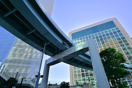 Photo for Pedi Shiodome shopping complex at the background of New Transit Yurikamome elevated railway line at Shiodome area of Minato. Tokyo. Japan - Royalty Free Image