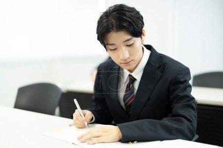 Photo for Japanese male school student studying in classroom - Royalty Free Image