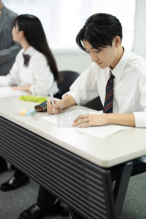 Téléchargez les photos : Japonais écoliers en uniforme étudiant en salle de classe - en image libre de droit
