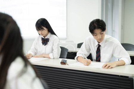 Foto de Estudiantes de escuela japonesa en uniforme estudiando en el aula - Imagen libre de derechos