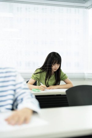 Photo for Pensive Asian schoolgirl studying in classroom - Royalty Free Image