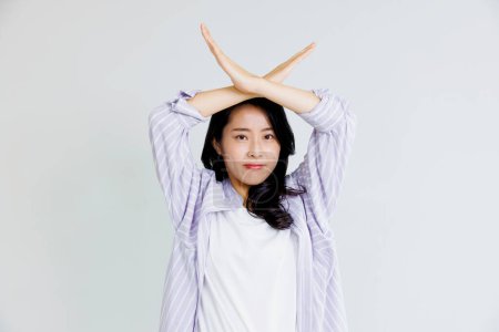 Foto de Retrato hermosa asiática mujer mostrando cruz gesto, detenerte, decir no contra blanco fondo - Imagen libre de derechos