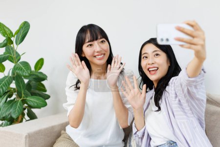 Photo for Happy asian woman taking selfie photo with friend at home - Royalty Free Image