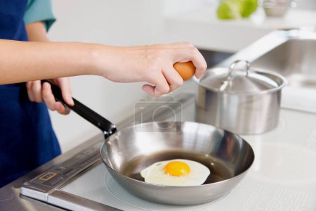 Téléchargez les photos : Femme cuisine les œufs à la main sur la casserole - en image libre de droit