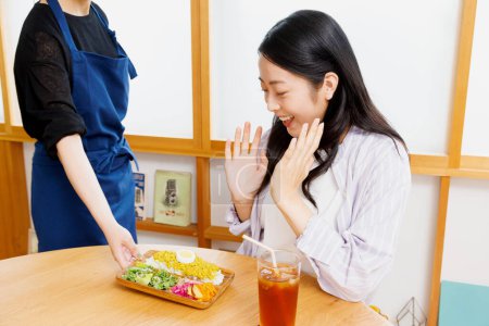 Photo for Asian woman is delighted with meal served by female waiter in restaurant - Royalty Free Image