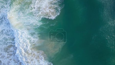 Téléchargez les photos : Vue de dessus d'une puissante vague dans l'océan turquoise. Photo de drone de vague mousseuse et bouclée pour le fond et la texture. Océan Indien, Bali est l'endroit idéal pour surfer. - en image libre de droit