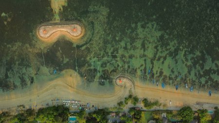 Foto de Vista de aves de la playa de Sanur en la isla de Bali. Atracción turística popular. Un terraplén creado artificialmente con curvas elegantes y gazebos. El arrecife protege la zona costera de las olas. - Imagen libre de derechos