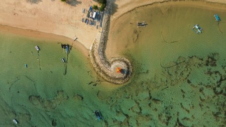 Foto de Vista aérea de la costa de la playa de Sanur en Bali. Gazebo en el terraplén rizado. Pescadores multicolores barcos están estacionados cerca de la orilla. Hermosa costa con agua plana de color turquesa. - Imagen libre de derechos