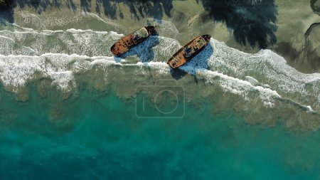 Photo for Aerial view of two abandoned ships off the shore of a Bali beach in the eastern part of the island. The sunken ship is covered with rust, a shipwreck. Cemetery of sunken ships on the island. - Royalty Free Image