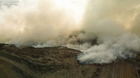 Foto de Vista aérea de un incendio catastrófico en un gran vertedero, quema de residuos plásticos. El humo venenoso sube al cielo y envenena el aire. Contaminación ambiental, desastre ecológico. - Imagen libre de derechos