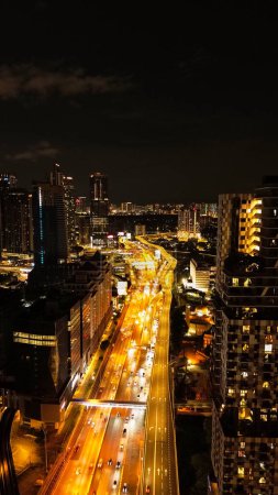 Foto de Vista aérea vertical de la ciudad nocturna de Kuala Lumpur en Malasia. Capital en el sudeste asiático. Vista de las calles a la luz de las luces de la noche, el tráfico en las carreteras por la noche. - Imagen libre de derechos