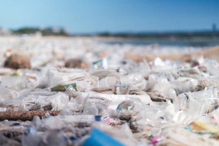 Close-up of a beach polluted with plastic waste. Global environmental disaster, mountains of garbage on the beach that came from the ocean. Empty used dirty plastic bottles and other chemical waste.