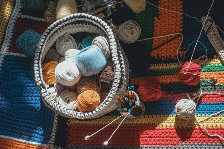 Téléchargez les photos : Vue de dessus d'un panier tricoté contenant des boules de fils de laine multicolores à côté se trouve un verre avec des aiguilles à tricoter et des crochets. Un passe-temps méditatif. Couverture bricolage. - en image libre de droit