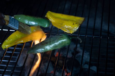 Téléchargez les photos : Poblano et jalapeno poivre rôtissant sur une grille de feu ouvert. Photo de haute qualité - en image libre de droit