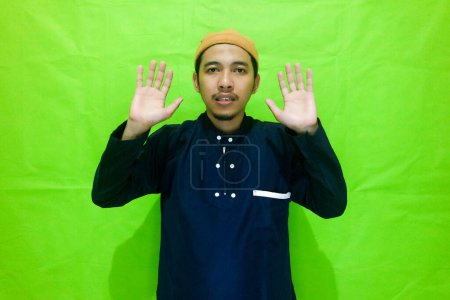 Asiatische muslimische Männer, die mit der Hand in der Brust stehen, machen Salat isoliert auf grünem Hintergrund