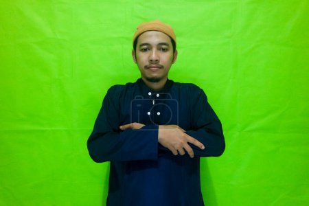 Asian muslim man standing with hand in chest are doing salat isolated on green background