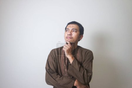 Téléchargez les photos : Musulman Asiatique homme expression sérieuse en pensant à quelque chose - en image libre de droit
