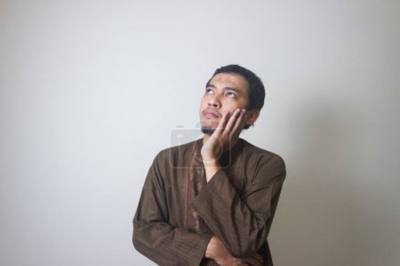 Téléchargez les photos : Musulman Asiatique homme expression sérieuse en pensant à quelque chose - en image libre de droit