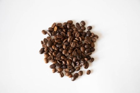 Foto de Granos de café marrón. Vista superior de un grupo de granos de café marrón en la superficie blanca. Aislado sobre fondo blanco. Enfoque selectivo. - Imagen libre de derechos