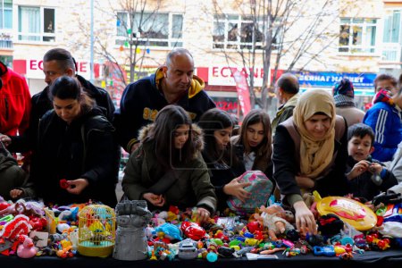 Foto de La gente examina los juguetes en un stand en bazar antiguo. Este bazar conocido como en turco "Ayranci Antika Pazari" - Imagen libre de derechos