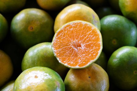 Foto de Mitad de mandarina en frente con otras mandarinas en segundo plano en el mercado de agricultores. Concepto de fruta idea. Enfoque selectivo. - Imagen libre de derechos