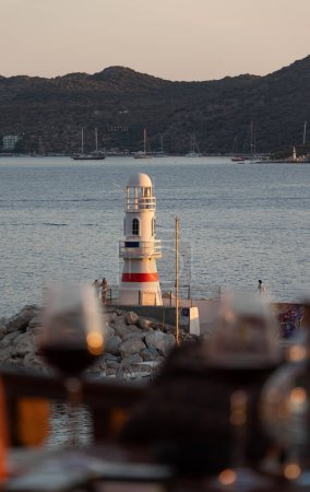 Foto de Faro. Foto vertical del paisaje del faro. Dos copas de vino en la mesa por la tarde con paisaje marino. Enfoque selectivo. - Imagen libre de derechos