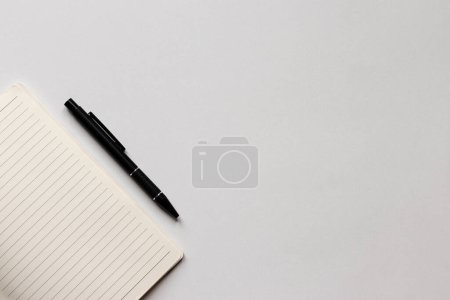 Foto de Vista superior de un cuaderno parcialmente forrado y un bolígrafo en el escritorio de la oficina blanca. Minimalismo, plano laico. - Imagen libre de derechos