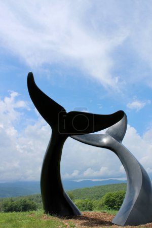 Photo for Sculpture of whale tails in front of green mountains - Royalty Free Image
