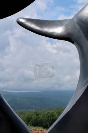 Photo for Sculpture of whale tails in front of green mountains - Royalty Free Image
