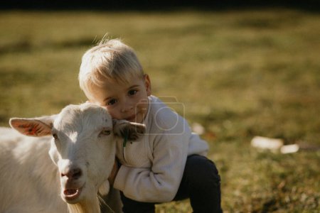 Téléchargez les photos : Jeune garçon et son petit fils jouent avec une vache dans le village. - en image libre de droit