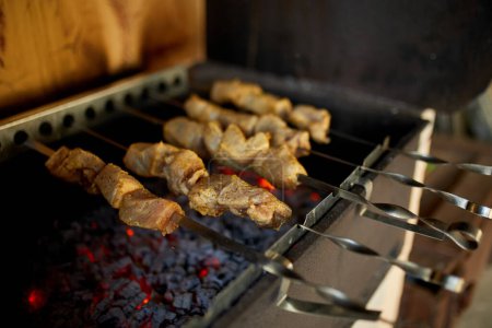 Foto de Agitadores de kebabs cocinan sobre las brasas calientes de una parrilla de barbacoa en un entorno de patio trasero casero, destacando una tradición culinaria de verano. - Imagen libre de derechos